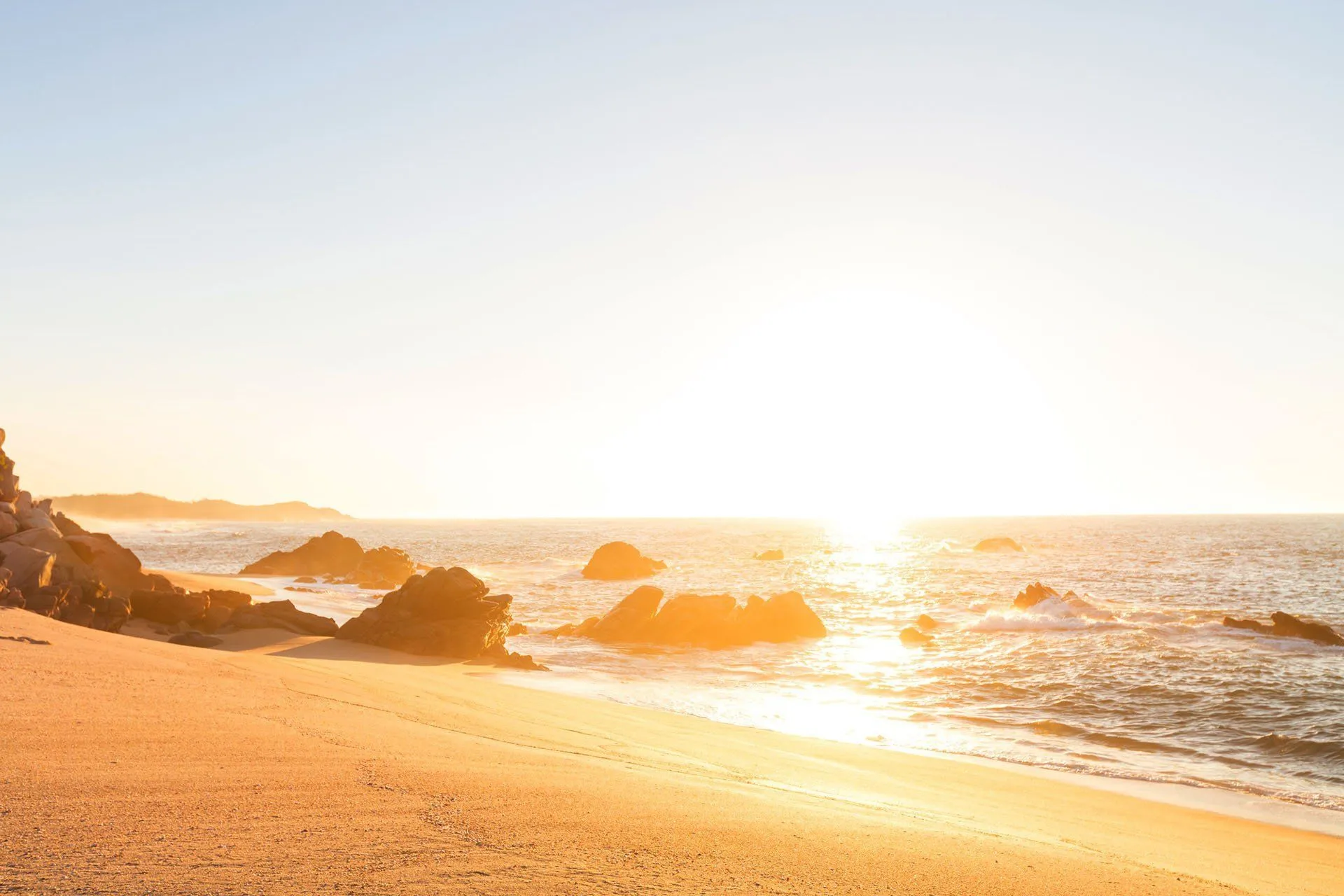 Soft golden sunrise over a calm shoreline, a quiet moment of reflection